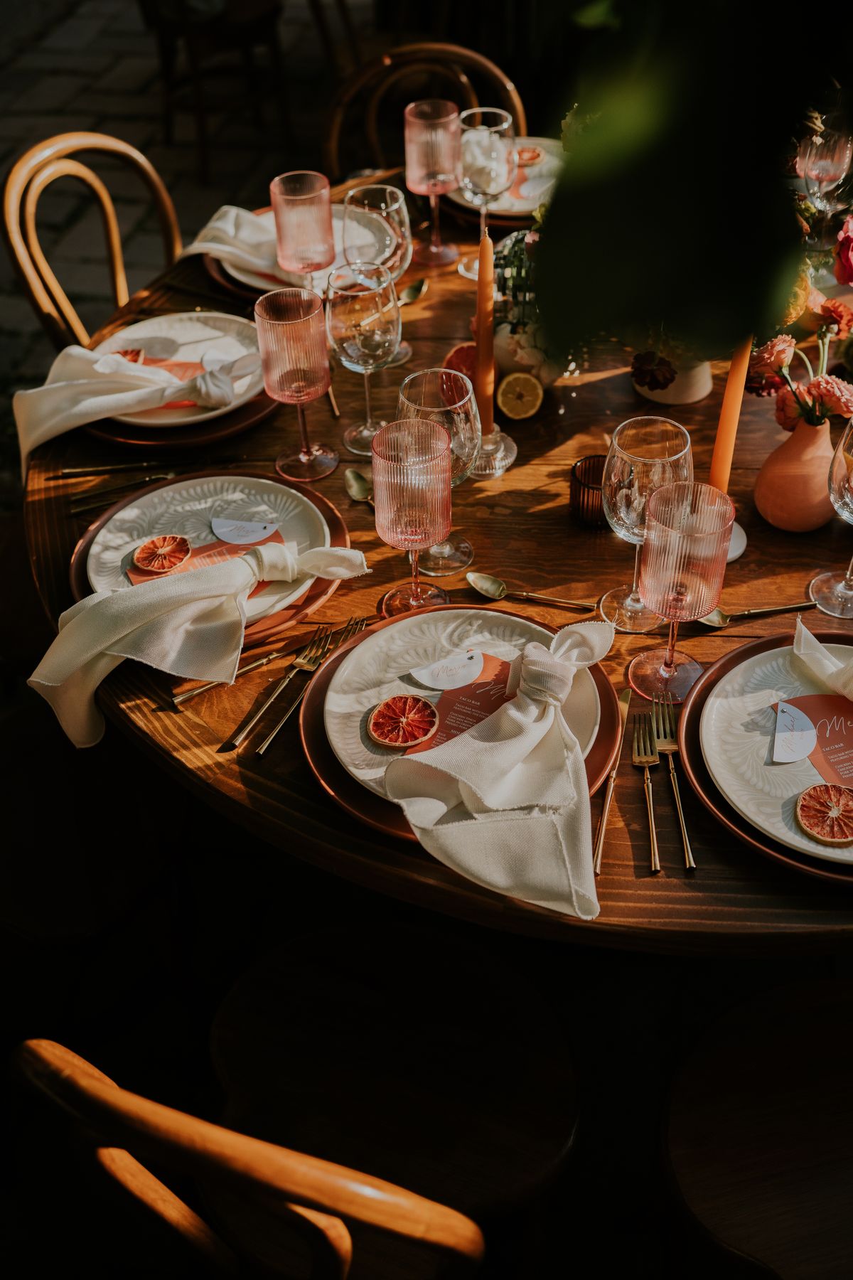 Wedding tablescape with citrus place settings, pink glassware, and candles